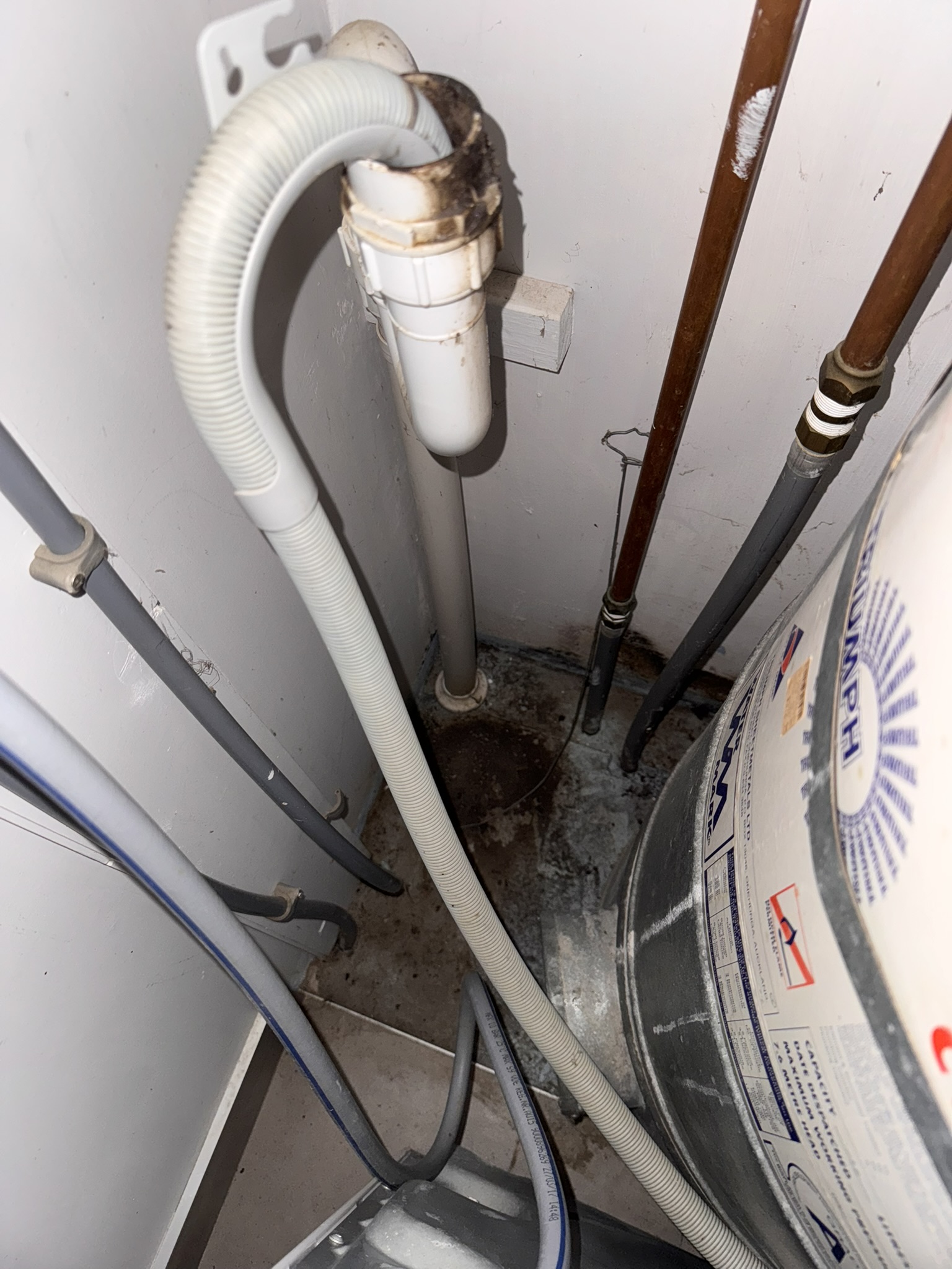 Moisture staining and residue around washing-machine waste pipes and floor